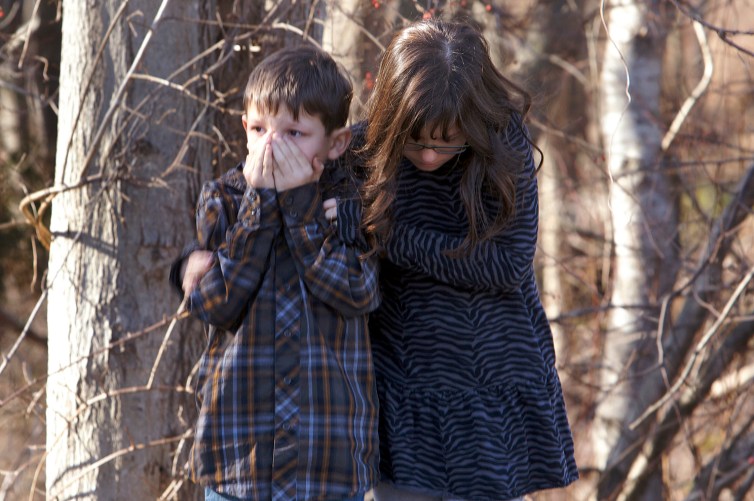 Young children wait outside Sandy Hook Elementary School after a shooting in Newtown